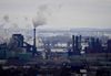 a large steel mill on the shore of lake ontario. the lake and steel bridges are visibile in the background