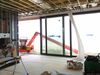 A residential construction job site with exposed studs in the walls and ceilings, and glass sliding doors open to a crane.